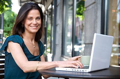 Young woman at laptop computer sitting outside working